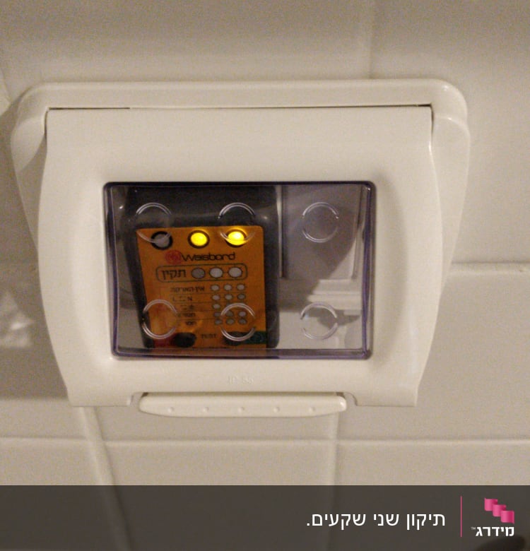 שקע חשמלי עם מכסה שקוף ומכשיר בדיקה